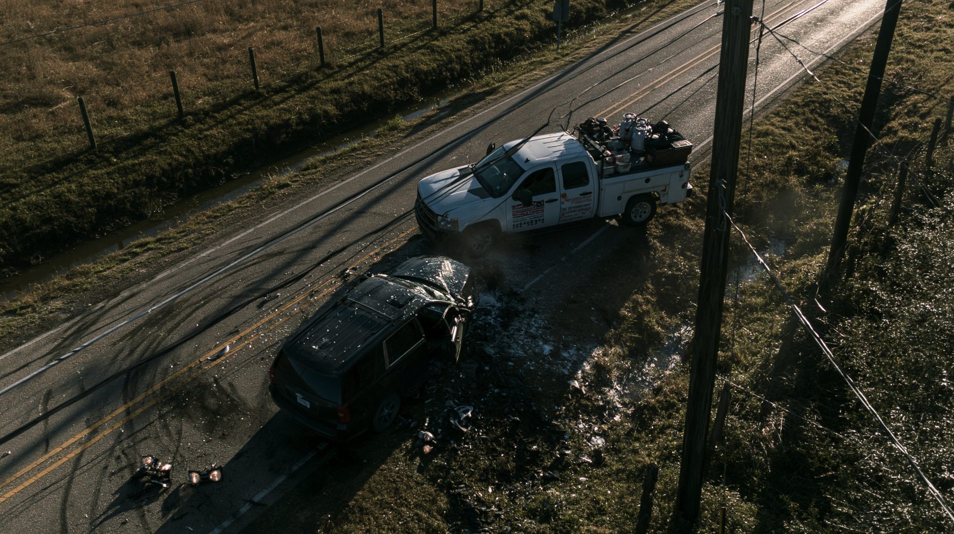 Aerial view of a two-vehicle collision on a rural highway with downed utility lines